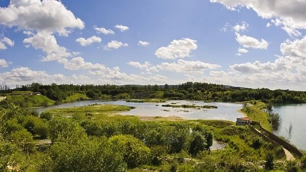 View of wetland habitat in flooded former chalk quarry, with birdwatching hide and visitor centre