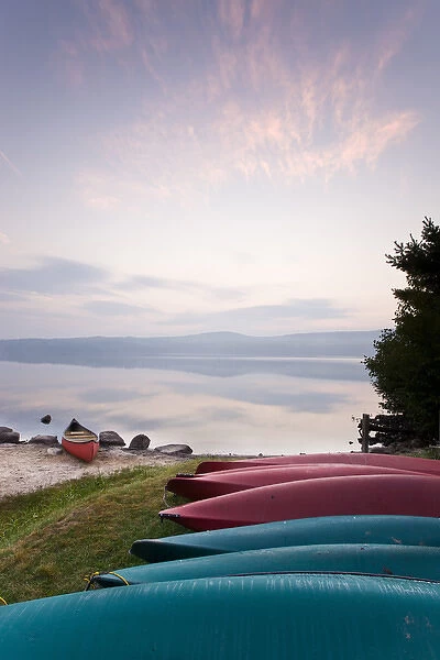 Canoes and kayaks on the shoreline of Lake Sunapee at sunrise at Mount Sunapee State