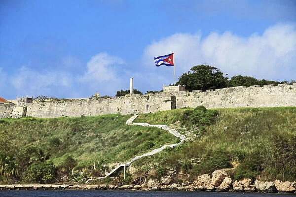 Cuba, Havana. Fortress wall and Cuban flag at San Carlos de la Cabana fortress in