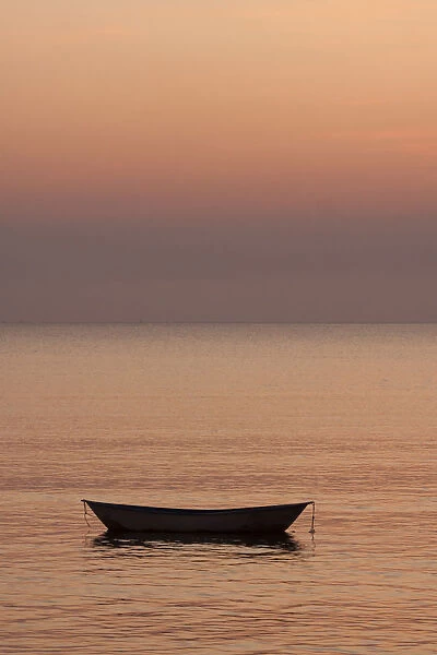 Rowboat at anchor in the water at sunset