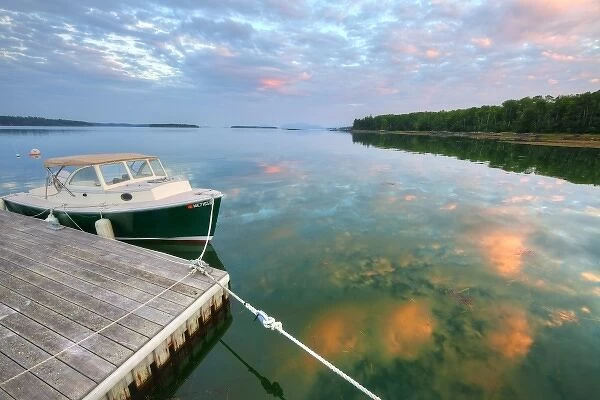 Small pleasure boat at dock while sunset clouds reflect in Sullivan Bay near Hancock