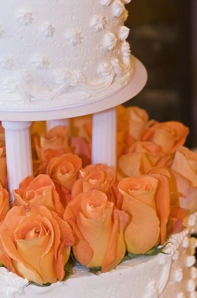 Detail of tiered wedding cake decorated with orange roses