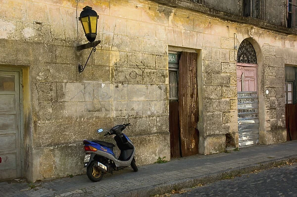 Uruguay. Colonia del Sacramento. Barrio Historico. Scooter outside an abandoned building