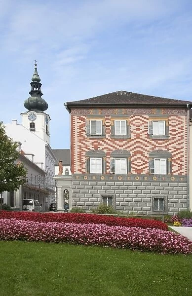 Wels, Upper Austria, Austria - Rows of red and pink flowers border a lawn in front of a building
