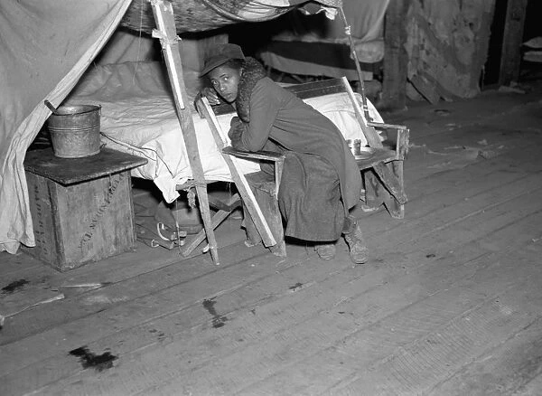 ARKANSAS: REFUGEE, 1937. An African American girl seated by her makeshift bed in