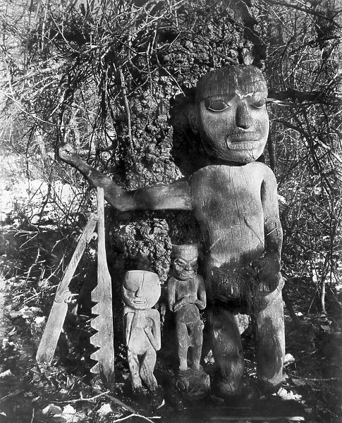 The grave of Shah, a Tlingit shaman, marked with carved wood totems, Chilkat, Alaska. Photographed by Winter and Pond, c1895