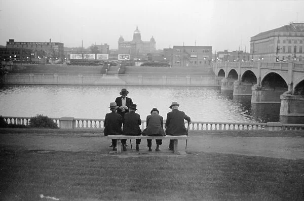 IOWA: DES MOINES, 1940. Men sitting on a bench along the Des Moines River, with