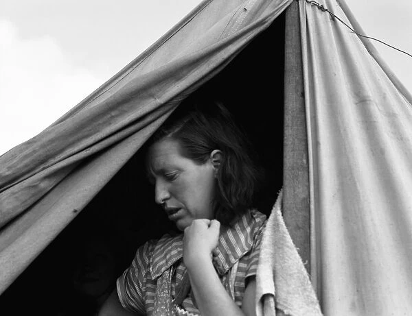 MIGRANT CAMP, 1939. A woman in the doorway of a tent at a camp for migrant workers