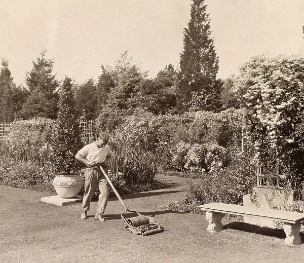 RHODE ISLAND: HOUSE, 1917. A gardener mowing lawn of the Beacon Hill House owned