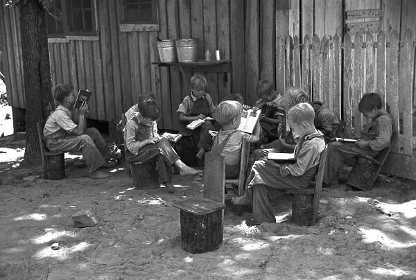 Schoolboys reading books in an outdoor classroom for migrant children at Skyline Farms, near Scottsboro, Alabama. Photograph by Carl Mydans, June 1936