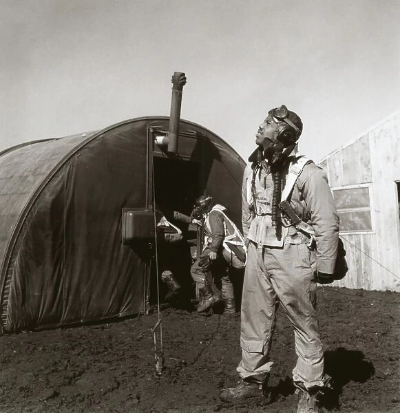 WWII: TUSKEGEE AIRMAN, 1945. Fighter pilot Newman Golden of the Tuskegee Airmen scans the skies. Behind him is the parachute room, at Ramitelli Airfield, Italy. Photograph by Toni Frissell, March 1945