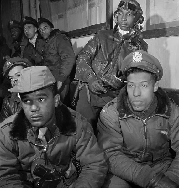 WWII: TUSKEGEE AIRMEN, 1945. A group of Tuskegee Airmen attending a briefing at Ramitella Airfield in Italy, March 1945. Left to right: Joseph Chineworth (partial view); Emile Clifton; Richard Harder. Along back wall (back to front): Frank Wright; Robert Murdic; Jimmie Wheeler. Photograph by Toni Frissell