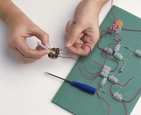 Boys hands attaching wires from connectors to terminals of variable resistor (building a radio circuit), close-up