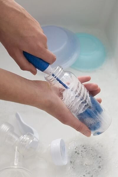 Hand scrubbing inside of baby bottle with a bottle brush, close-up