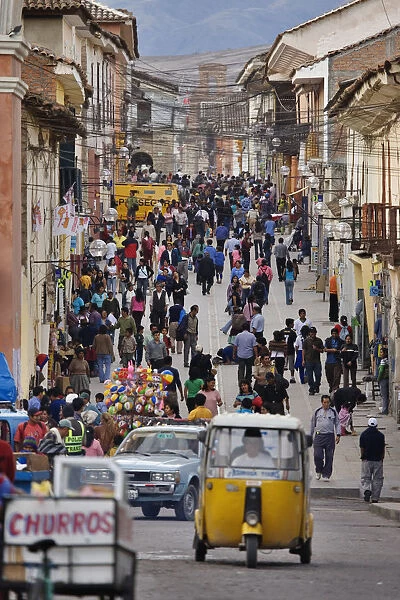 Peru, Ayacucho, street crowded with pedestrians, car and auto rickshaw, on 28 July, Independence Day