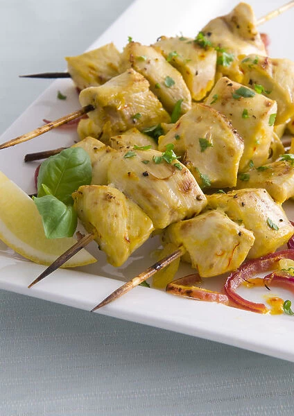 Saffron chicken brochettes, served with fresh lemon and basil, close-up