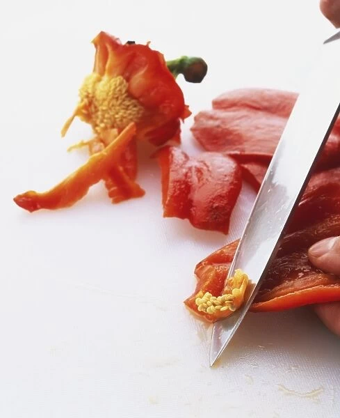 Scraping away the seeds of a red pepper, using a small, sharp knife