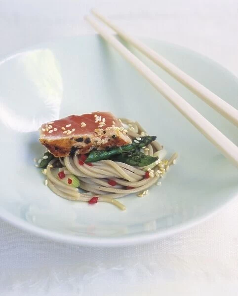 Seared salmon served with chilled soba noodles and asparagus in bowl with sesame seeds and chopsticks