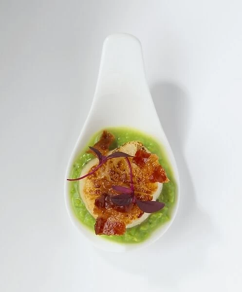 Seared scallop, pea puree and crispy pancetta on a ceramic spoon