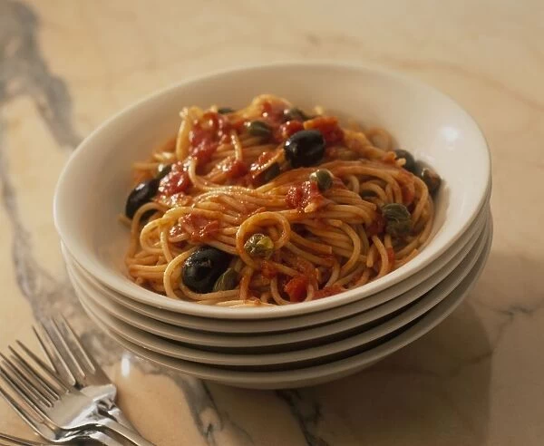 Spaghetti Puttanesca in bowl and a stack of bowls underneath