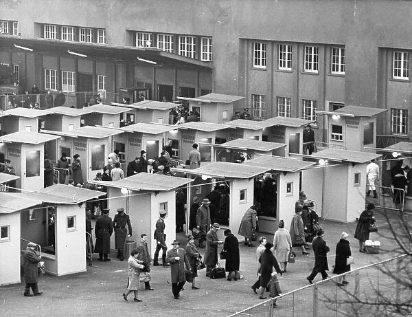 West berliners crossing over to visit relatives in east berlin in accordance with a recently signed treaty allowing such visits, october 1964, pictured are the customs booths at the friedrich strasse checkpoint set up specifically to handle the traffic