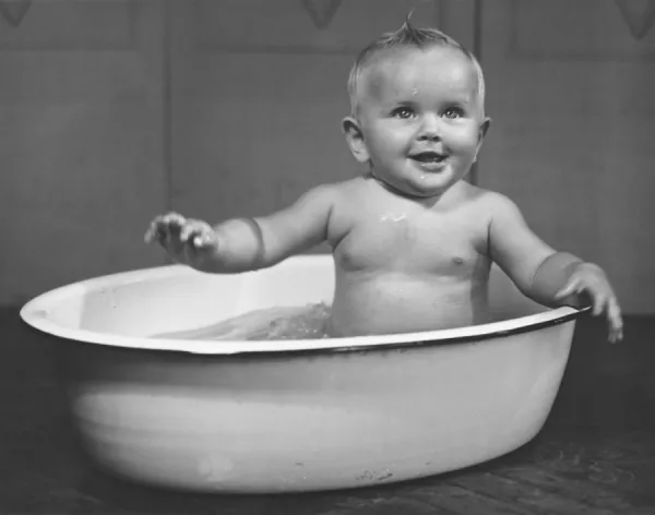 Baby boy (6-9 months) bathing in basin (B&W)