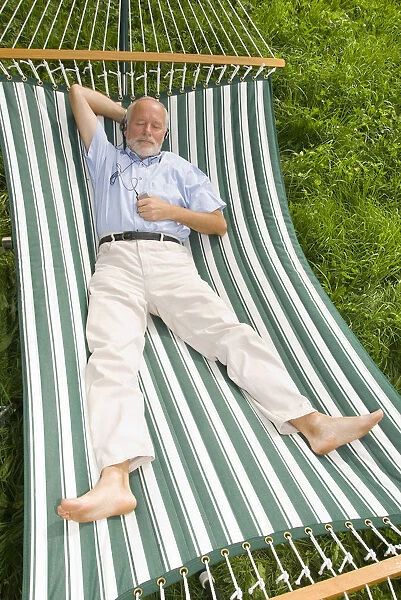 Elderly gentleman lying in a hammock and listening to music