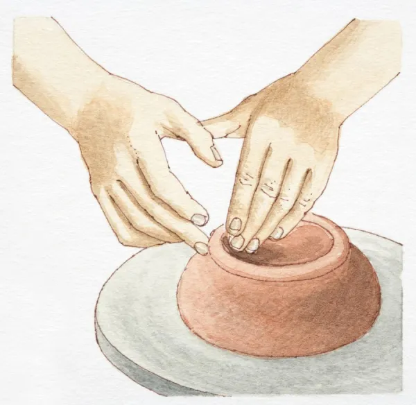 Hands molding clay on wheel