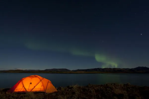 Illuminated expedition tent, Northern lights, Polar Aurorae, Aurora Borealis, green, reflections in water, Lake Laberge, near Whitehorse, Yukon Territory, Canada