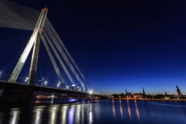 Latvia, Riga, River Daugava, Illuminated Vansu Bridge reflecting in river
