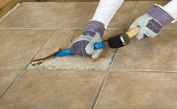 Man using club hammer and chisel to remove marble tile from floor, close-up
