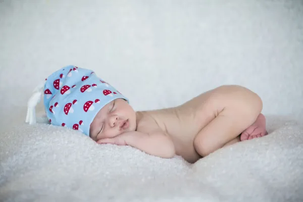 Newborn baby, 3 weeks, sleeping, wearing a hat