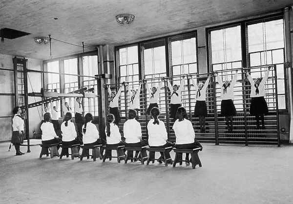 PE Class. A group of schoogirls attend a gym class, circa 1930