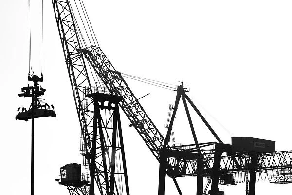 Silhouetted profile of construction cranes