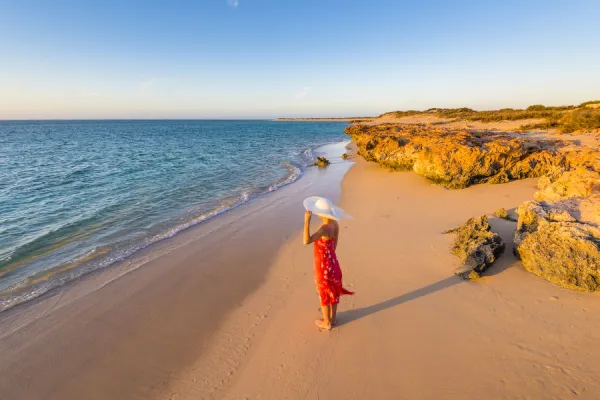 Woman with red dress on Osprey Bay beach at sunset. Western Australia