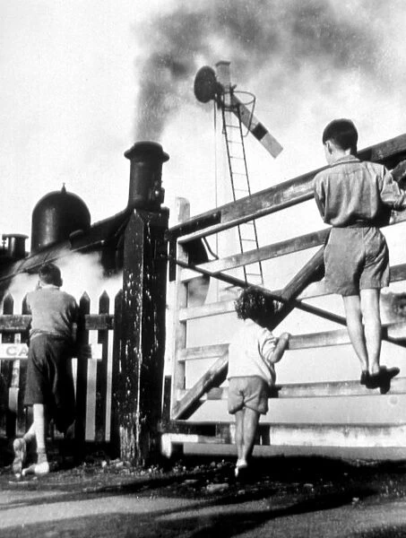 Steam train - children climbing gate to watch steam train go by - signal is down