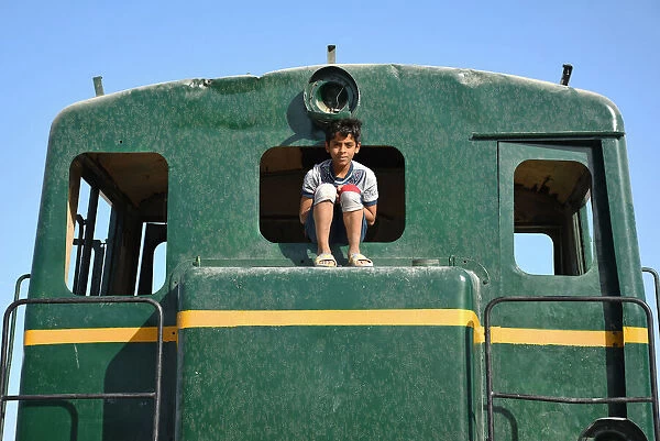 IRAQ-TRANSPORT. A boy sits on the window of a locomotive in the city of