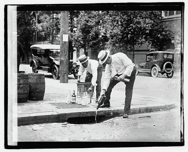 1920's - Pouring whiskey into a sewer during Prohibition (b / w photo)