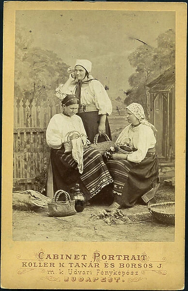 Budapest: Three peasant women photographed in the studio in traditional dress with headdress, basket and fabrics, 1870