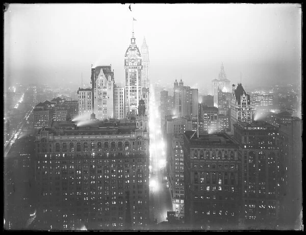 High-angle misty night view of lower Manhattan looking north, with the Singer Building