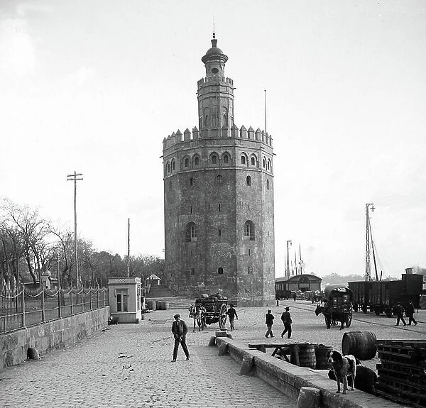Spain, Andalusia, PR, Seville: the gold tower, next to the quay of the Guadalquivir where there are iron voices, horse-drawn cars and goods ready to be loaded on ships, 1890