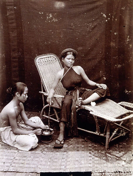 Vietnamese woman relaxes smoking a pipe. Colonial, Vietnam, , 1895 (b / w photo)