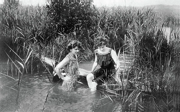 Two young women in swimsuits bathing in a river. 1900 circa Germany Historic photograph, women bathing, bathing costumes from around 1900