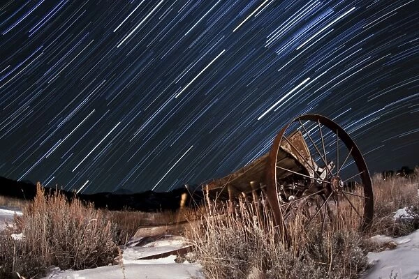 Abandoned farm equipment against a backdrop of star trails
