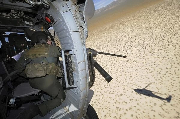 An aerial gunner scans terrain for training targets from an HH-60 Pave Hawk