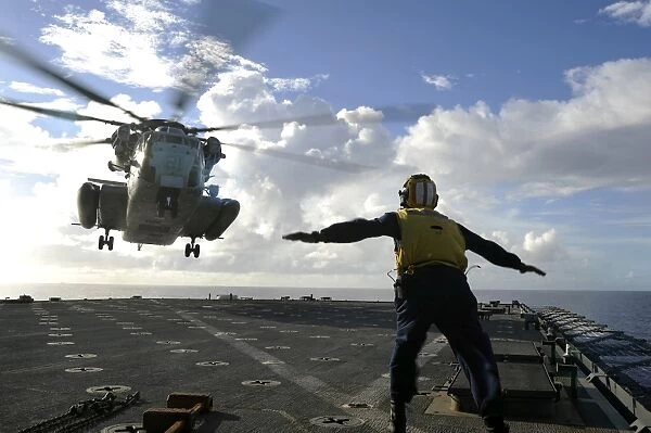 Aviation Boatswains Mate directs a CH-53E Super Stallion onto the flight deck of