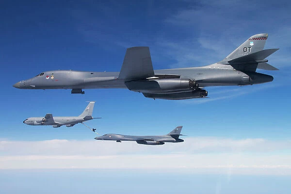 A B-1B Lancer stands by as another Lancer connects with a KC-135 Stratotanker