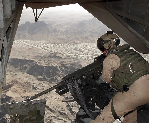 A crew chief aims the GAU-21. 50 caliber machine gun out the tail of a CH-53E Super