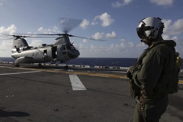 A crew chief watches a CH-46E Sea Knight helicopter aboard USS Makin Island