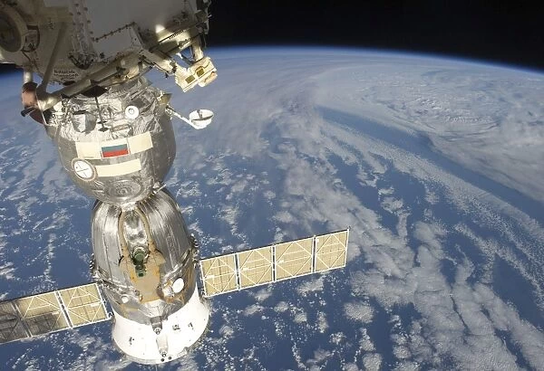 A docked Russian Soyuz spacecraft backdropped by Earth